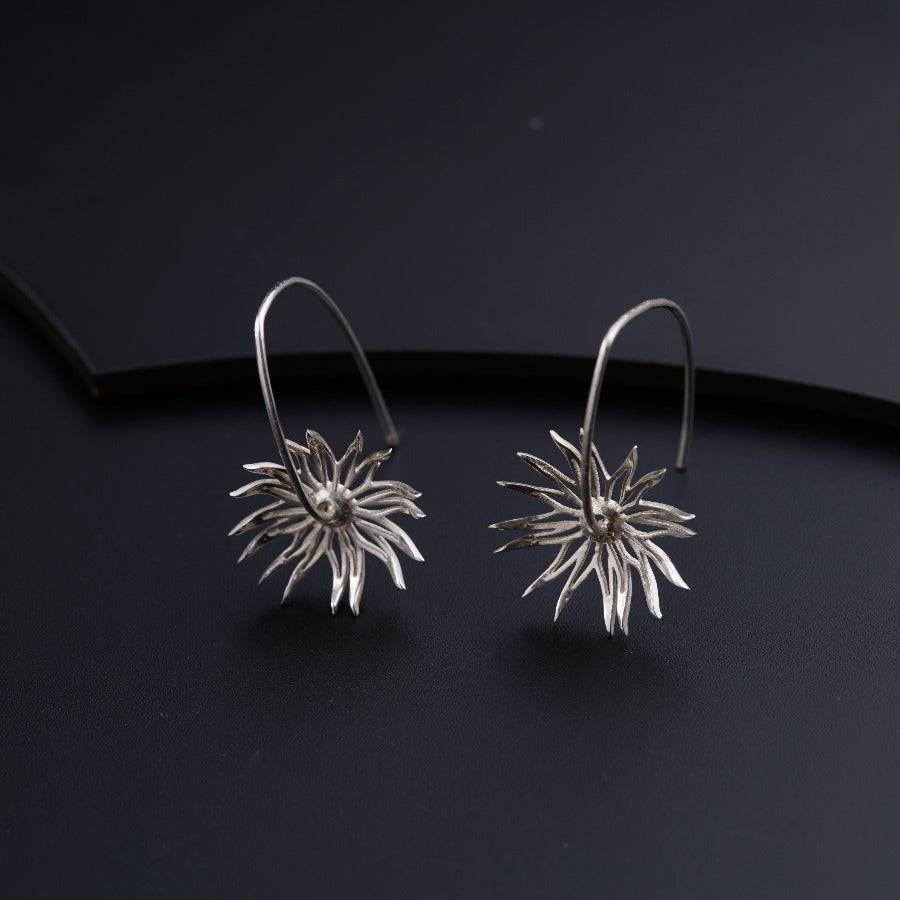 a pair of silver earrings on a black surface