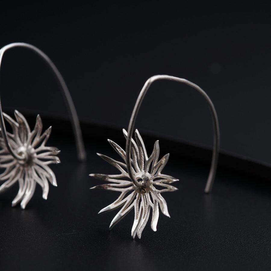 a pair of silver earrings on a black surface