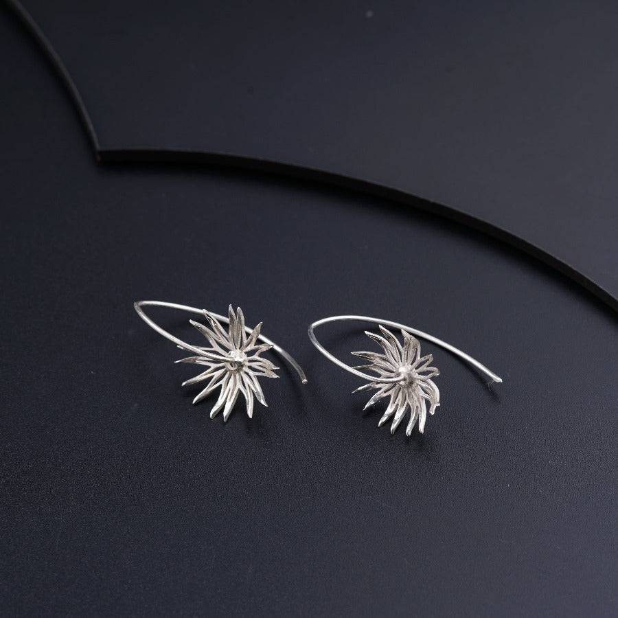 a pair of silver earrings on a black surface