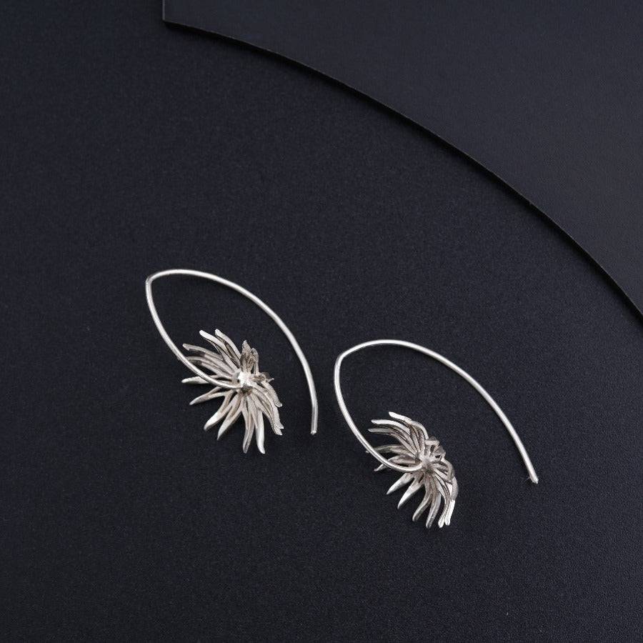 a pair of silver earrings on a black surface