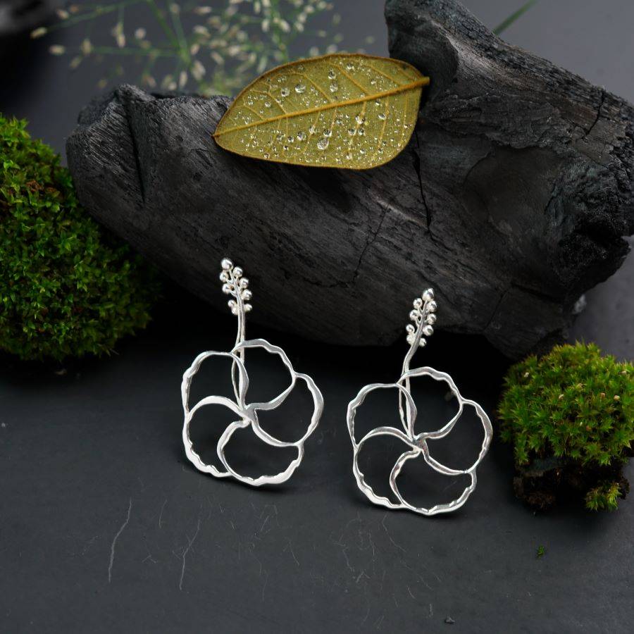 a pair of silver earrings sitting on top of a tree branch