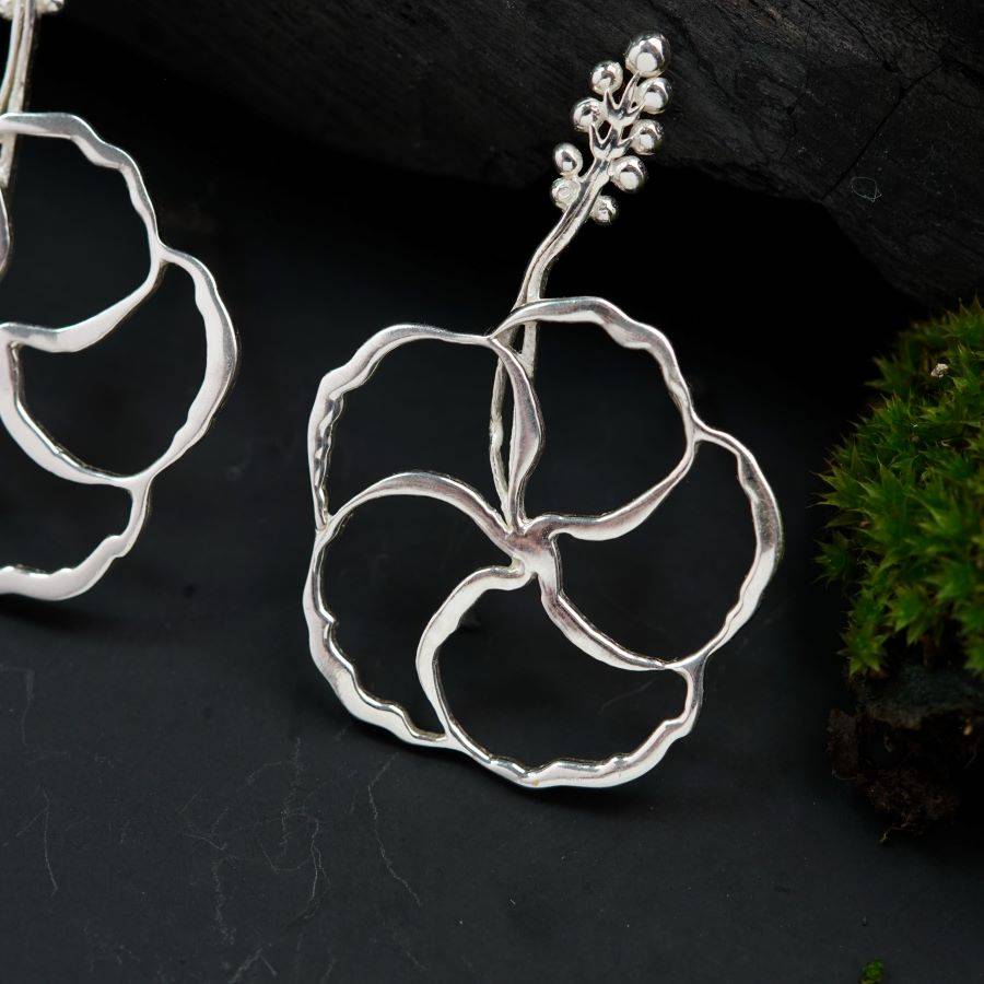 a pair of silver earrings sitting on top of a table