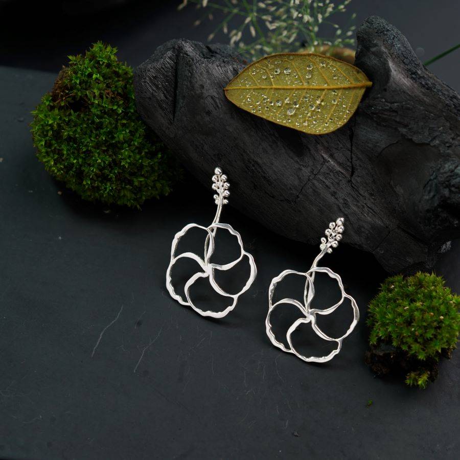 a pair of silver earrings sitting on top of a rock