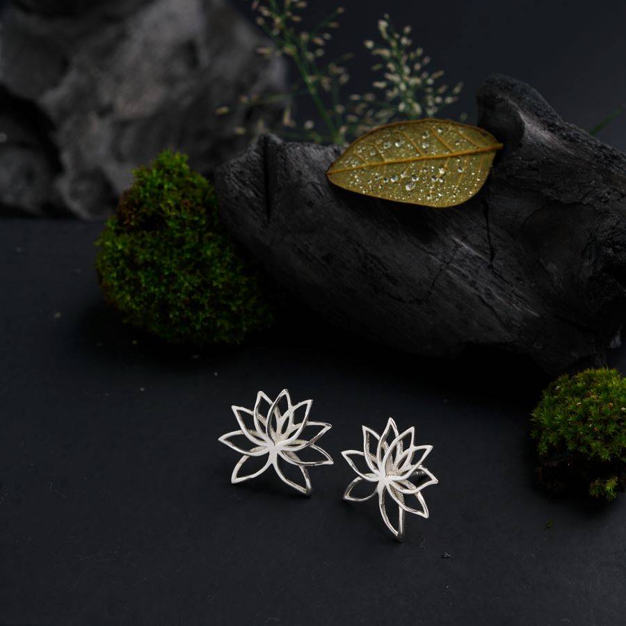 a pair of earrings sitting on top of a piece of wood
