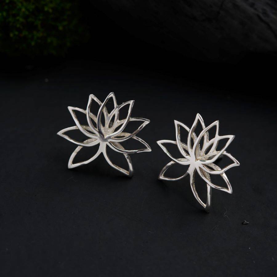 a pair of silver lotus earrings on a black surface