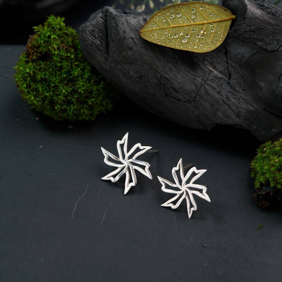 a pair of silver snowflake earrings on a black surface