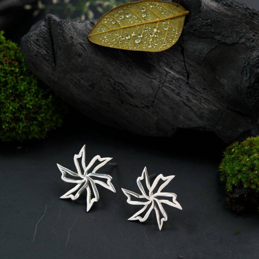 a pair of silver earrings with a leaf design