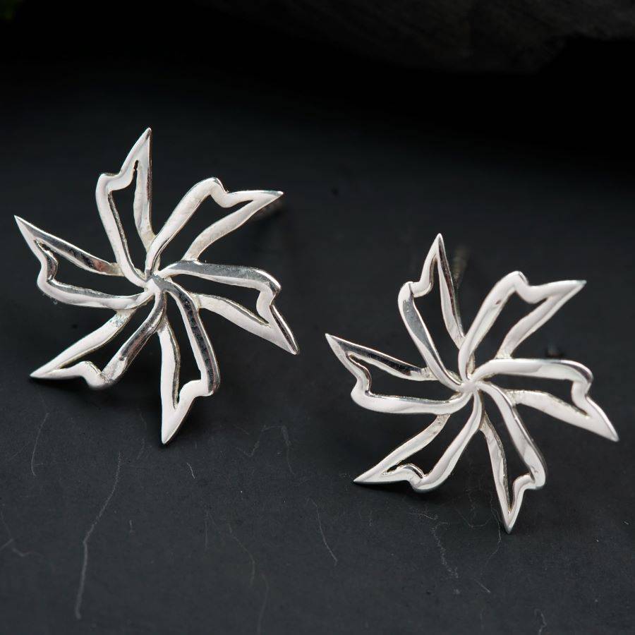 a pair of silver earrings sitting on top of a table