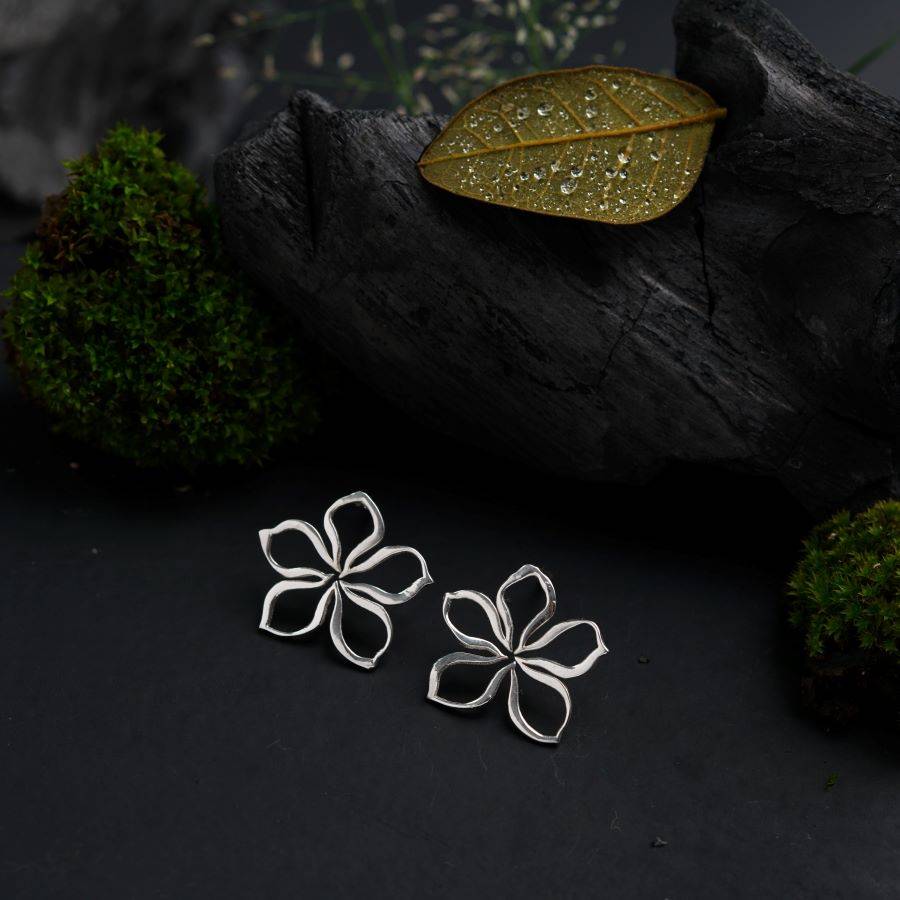 a pair of earrings with a leaf on top of it