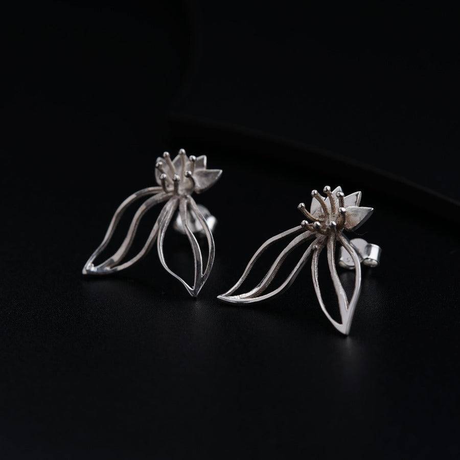 a pair of silver earrings on a black surface