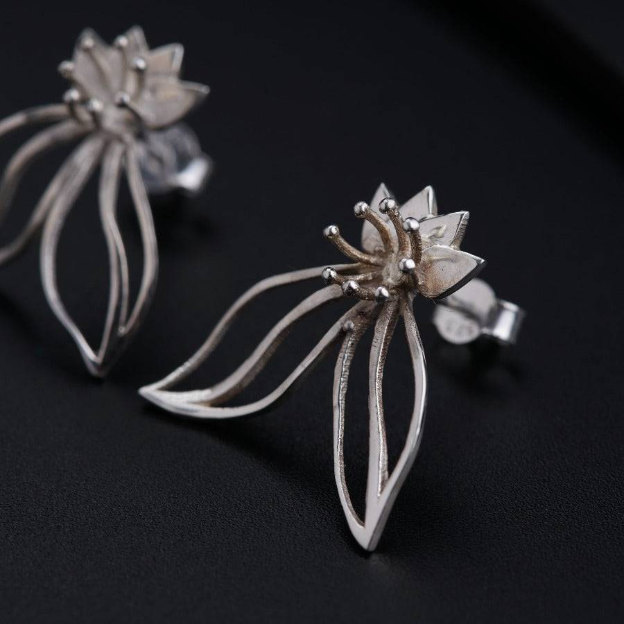 a pair of silver earrings on a black surface