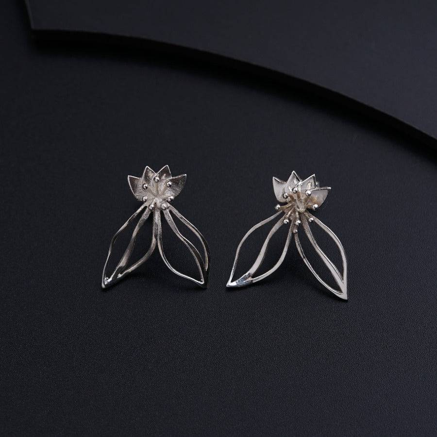 a pair of silver earrings on a black surface