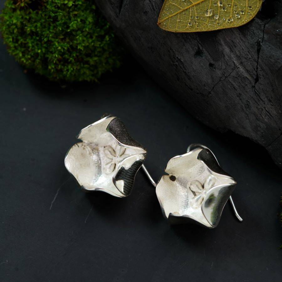 a pair of silver earrings sitting on top of a table