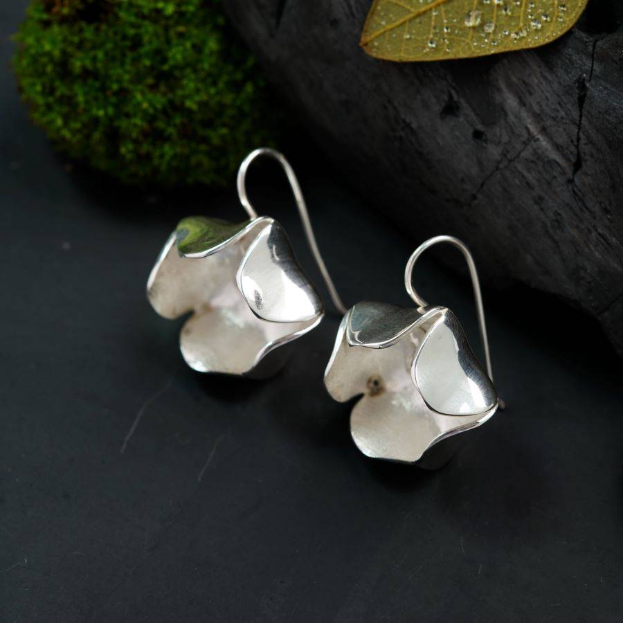 a pair of silver earrings sitting on top of a table