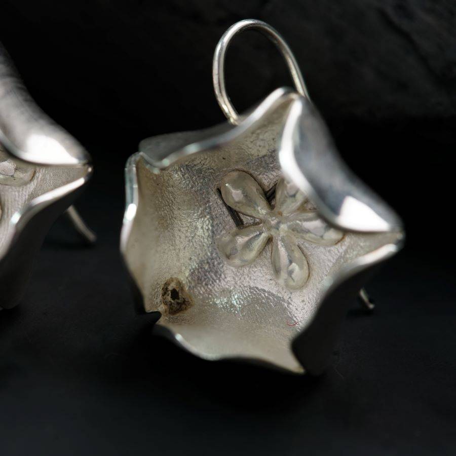 a pair of silver earrings sitting on top of a table