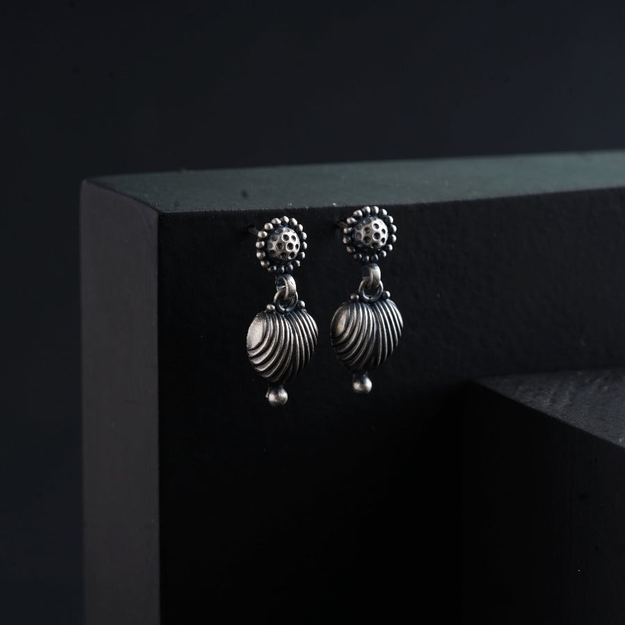 a pair of silver earrings on a black surface
