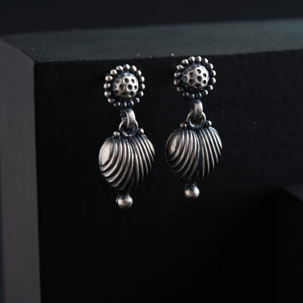 a pair of silver earrings sitting on top of a black box