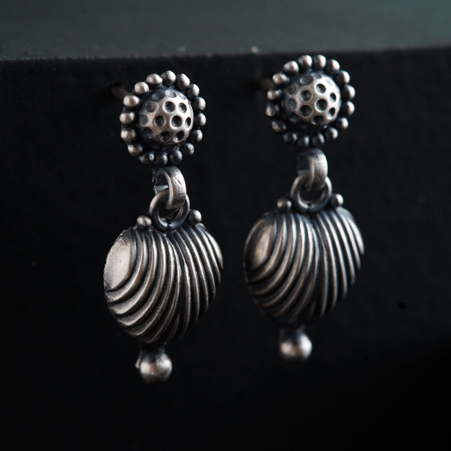 a pair of silver earrings sitting on top of a black surface