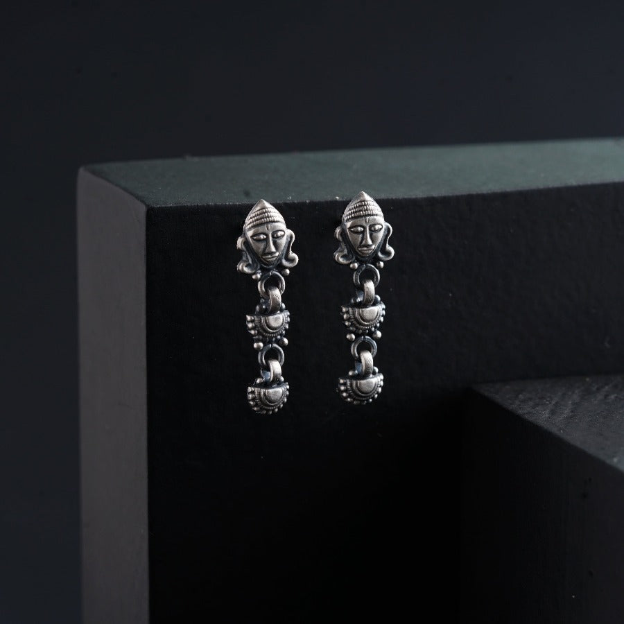 a pair of silver earrings sitting on top of a black box