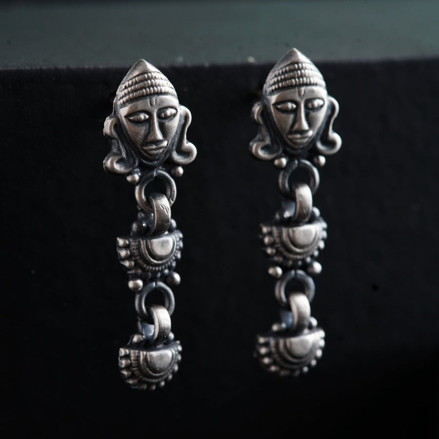 a pair of silver earrings with a face on it