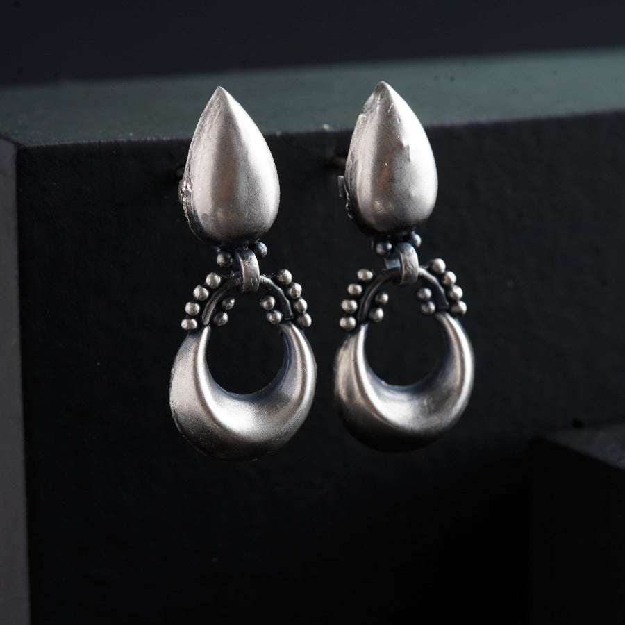 a pair of silver earrings hanging from a hook