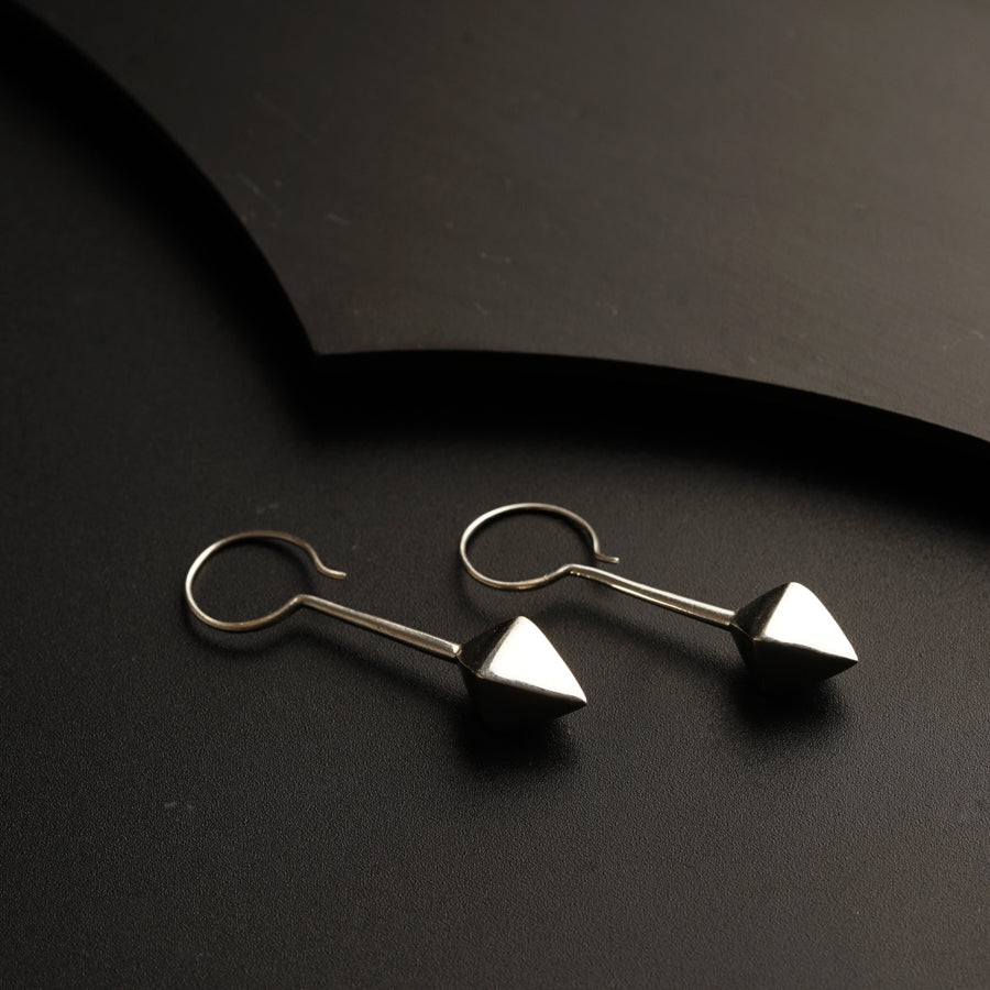 a pair of silver earrings sitting on top of a table