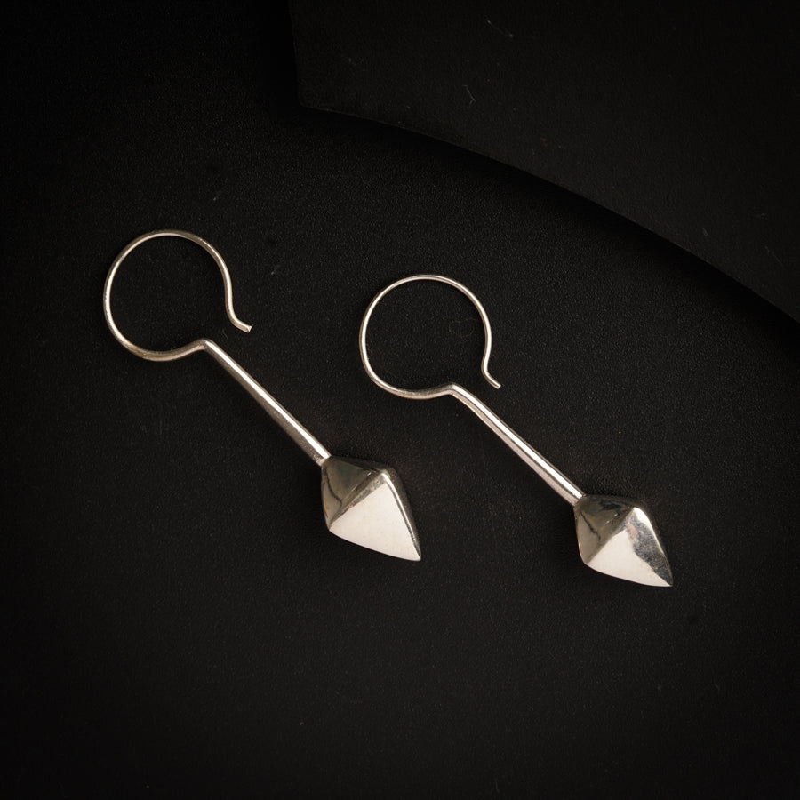 a pair of silver earrings sitting on top of a black surface