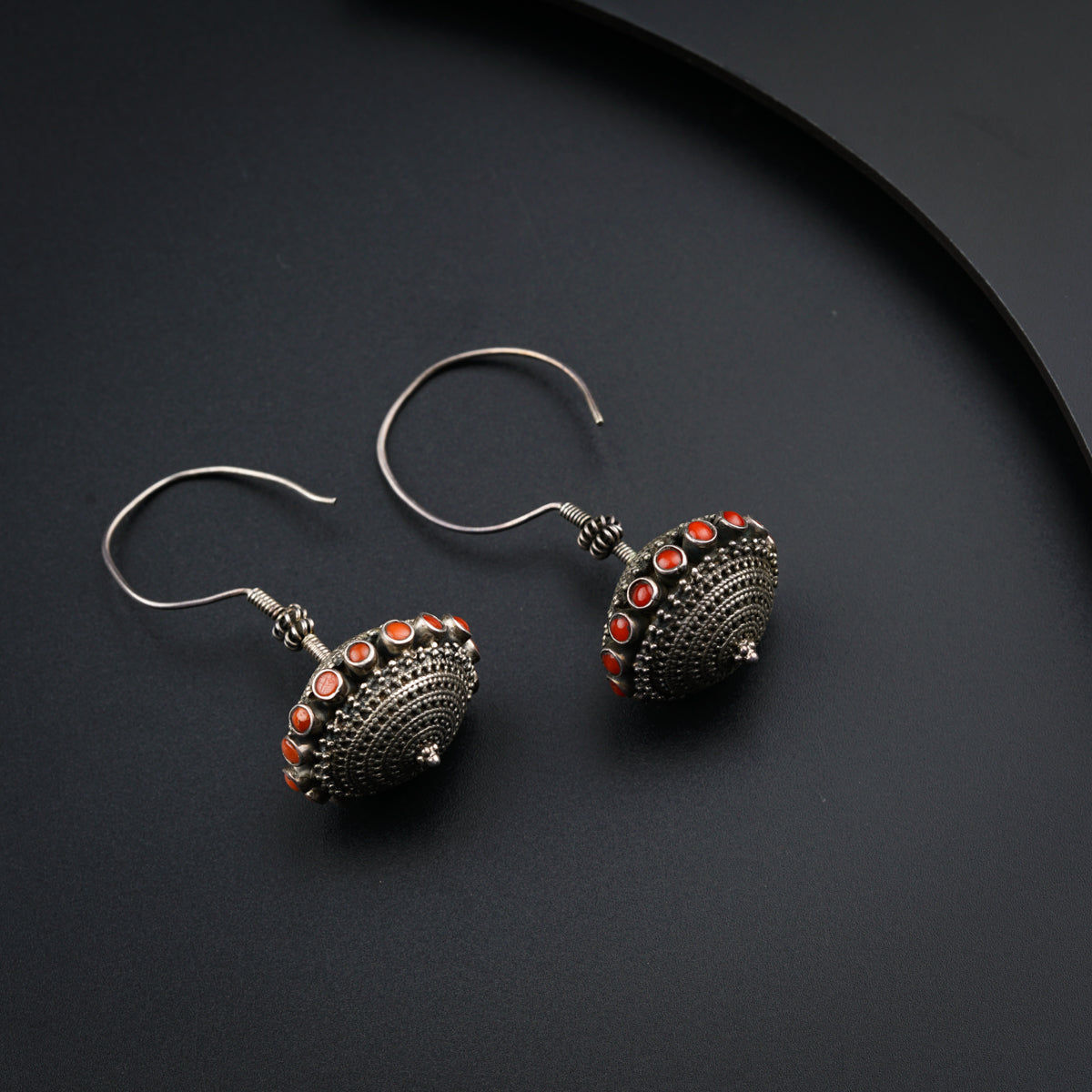 a pair of silver earrings with red beads