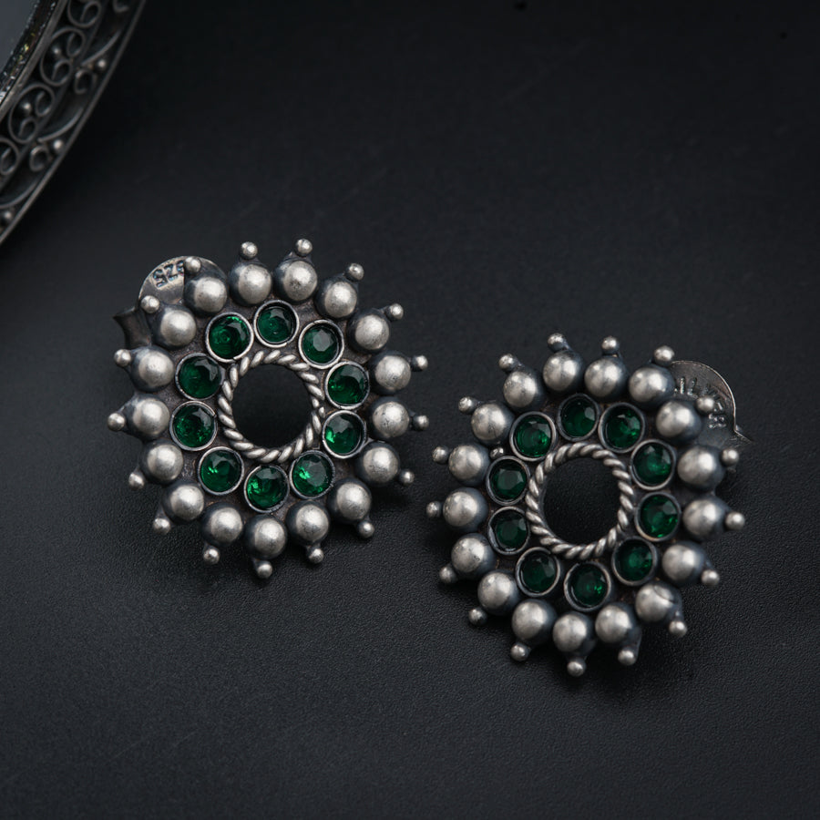 a pair of green and silver earrings on a black surface