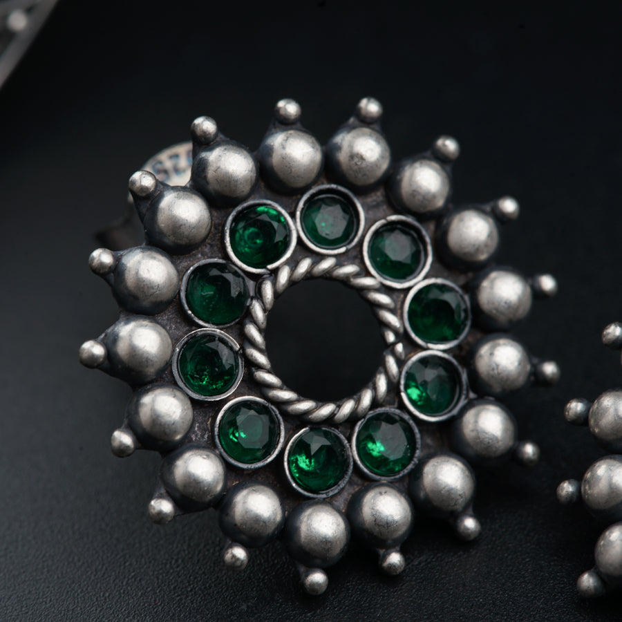 a close up of a ring with green stones
