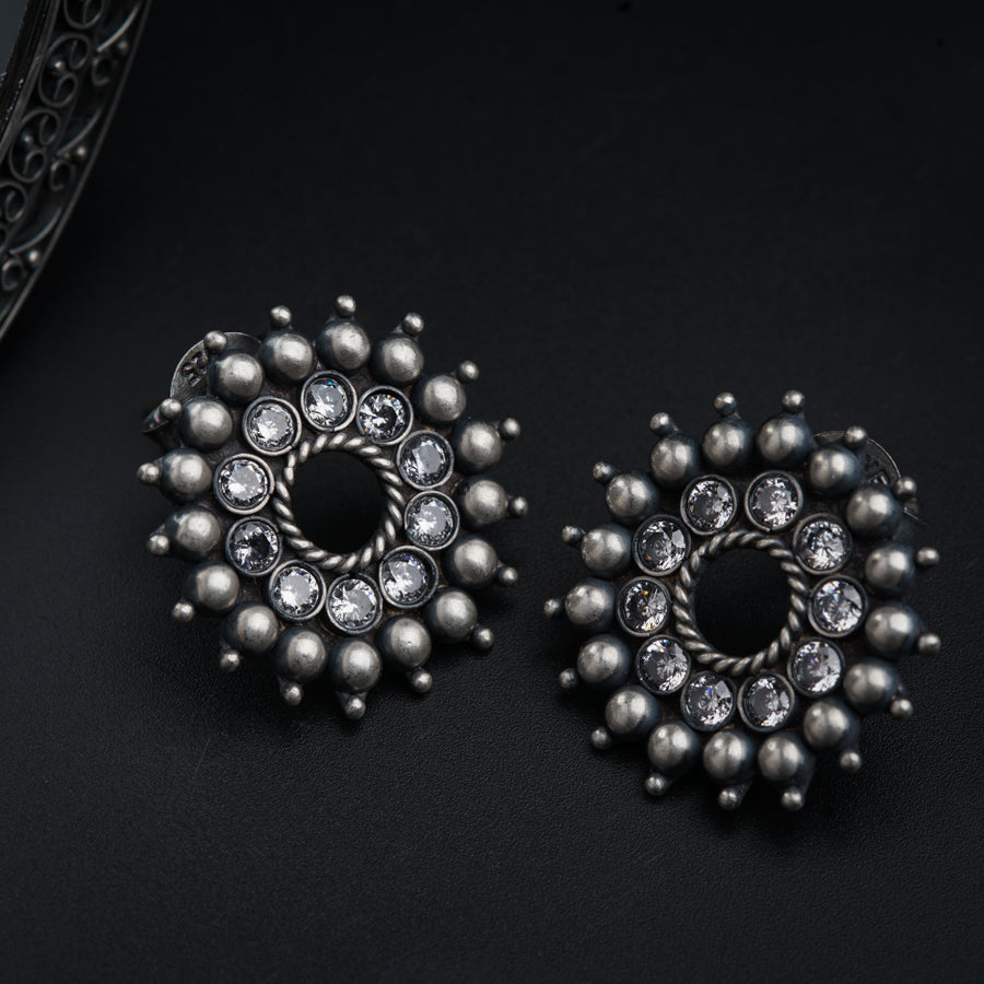 a pair of silver earrings on a black surface