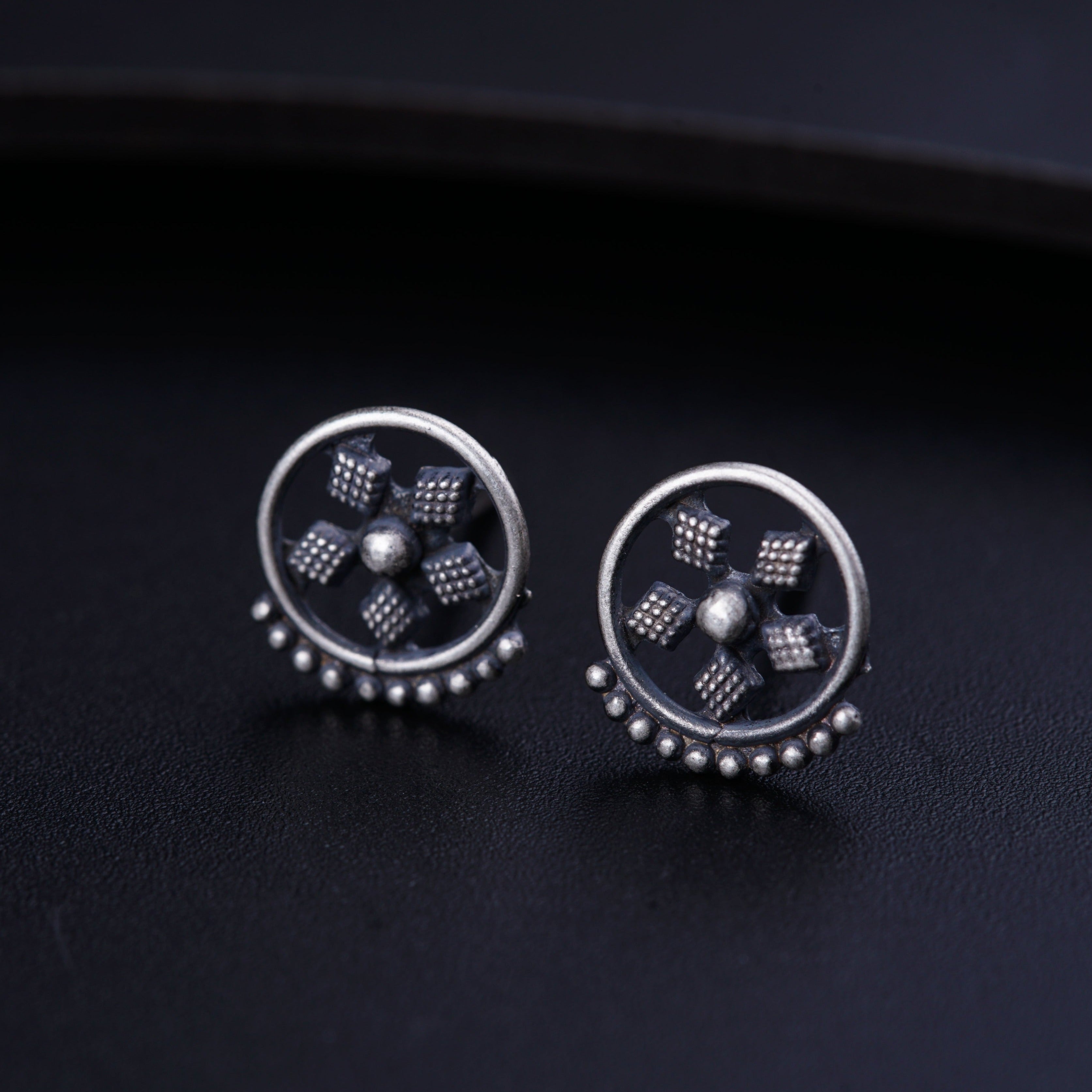 a pair of silver earrings on a black surface