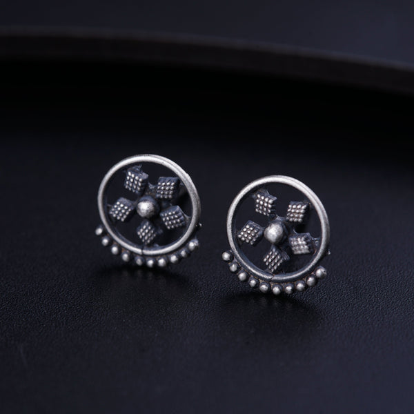 a pair of silver earrings on a black surface