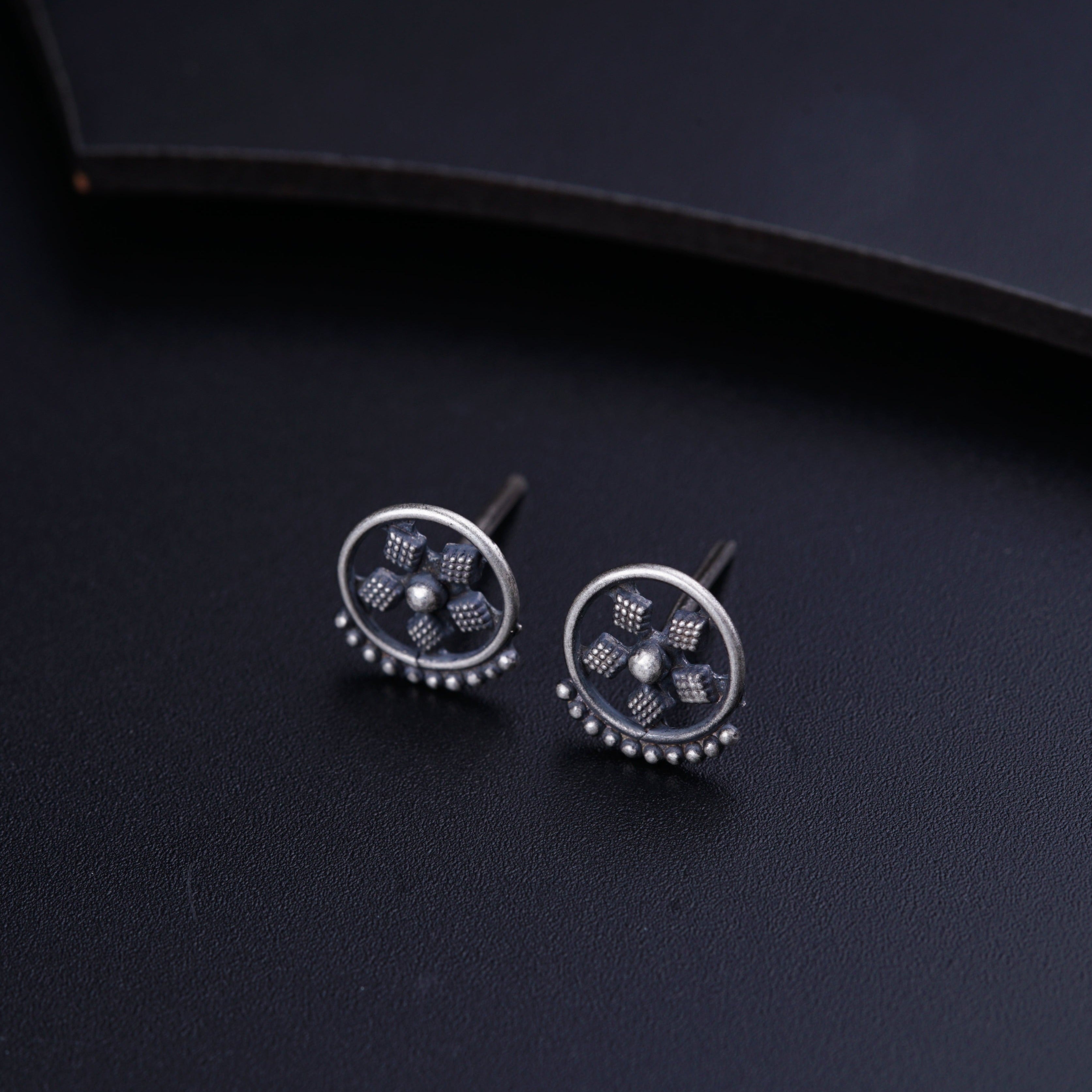 a pair of silver earrings on a black surface