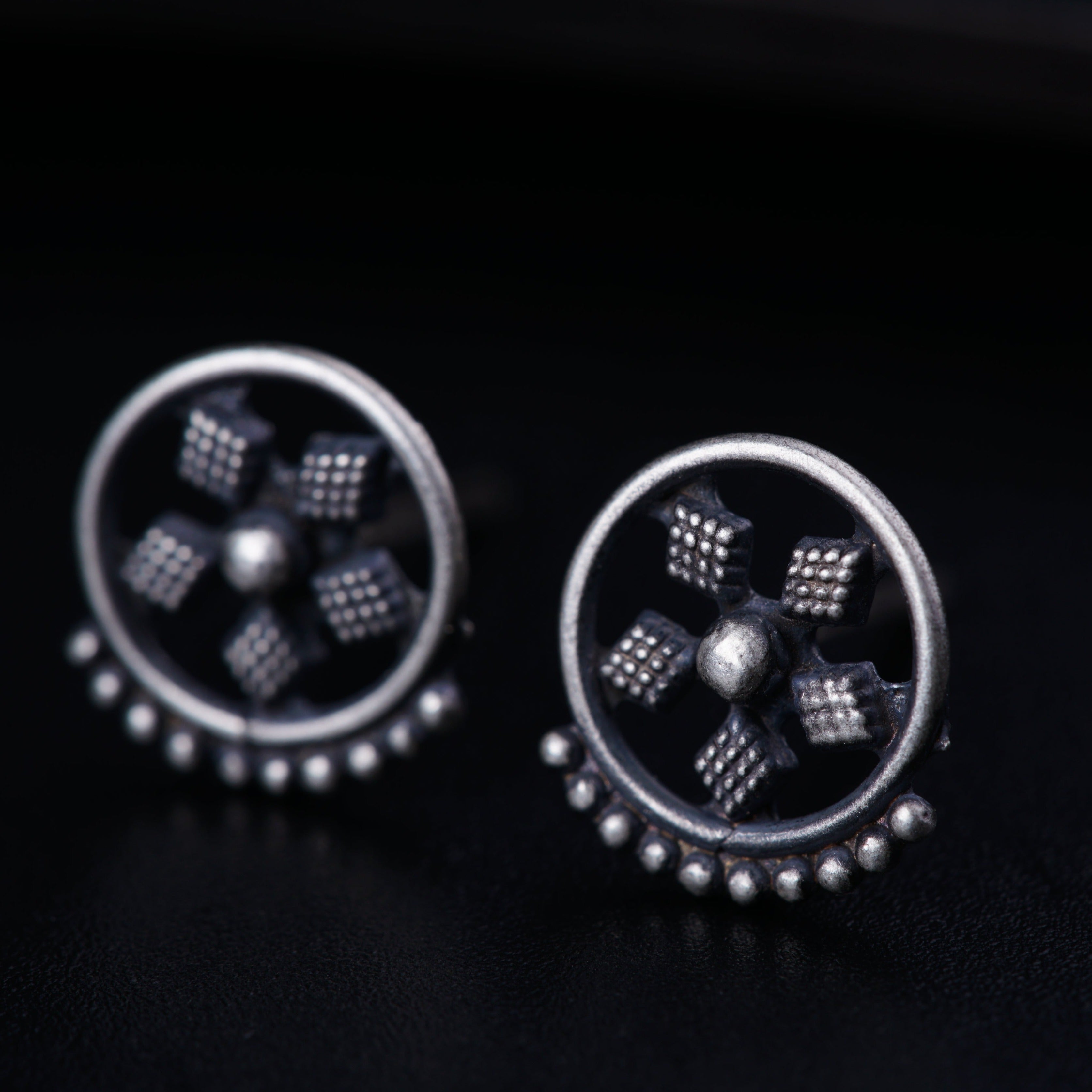 a pair of studded earrings on a black surface