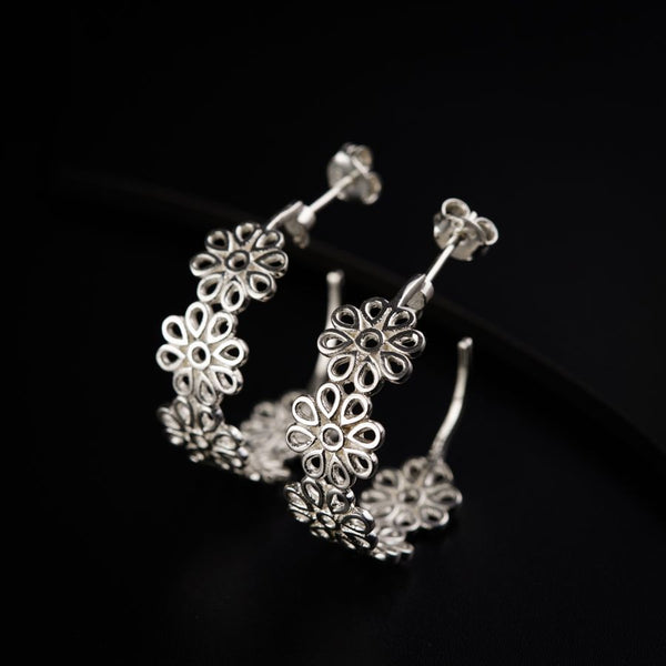 a pair of silver hoop earrings on a black surface