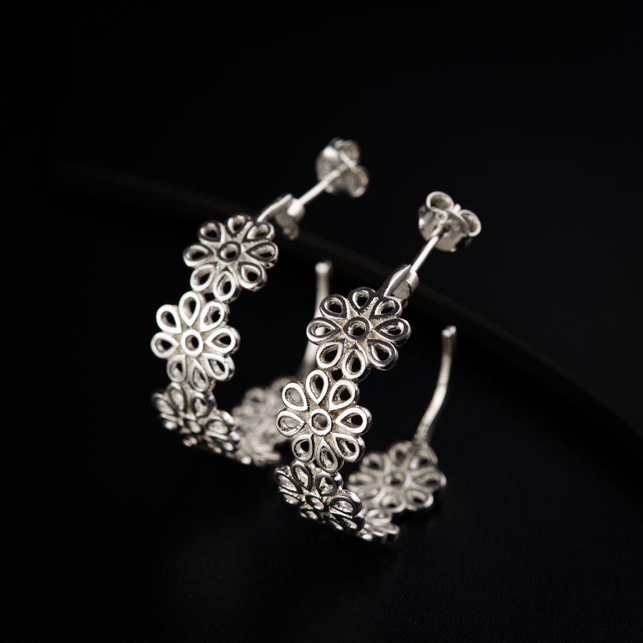 a pair of silver hoop earrings on a black surface