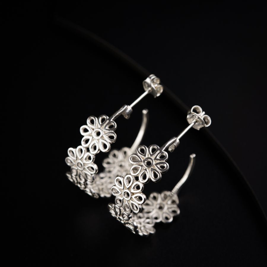 a pair of silver earrings on a black surface