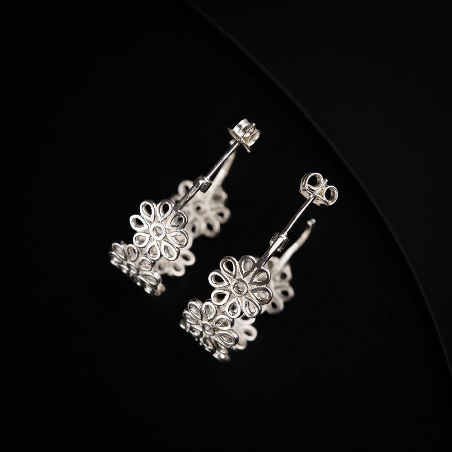 a pair of silver earrings on a black background