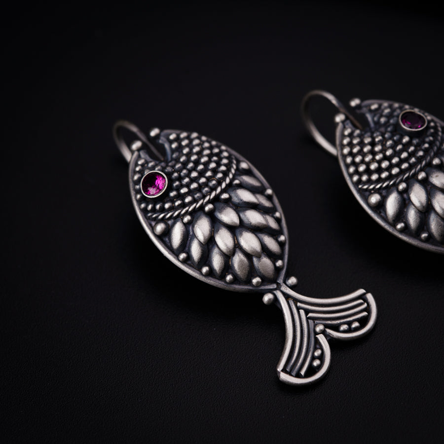 a pair of fish shaped earrings with pink stones