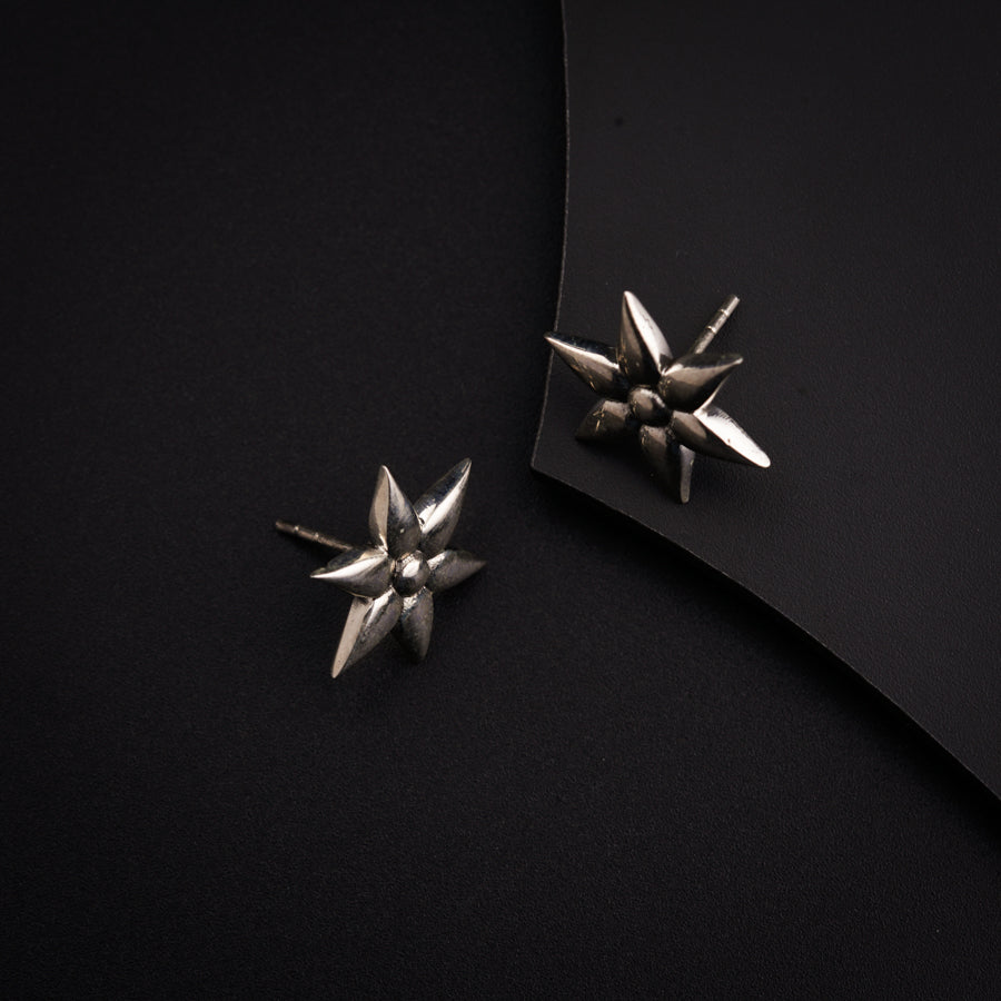 a pair of silver earrings sitting on top of a black surface