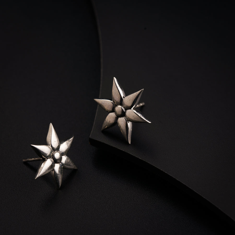 a pair of silver earrings sitting on top of a black surface