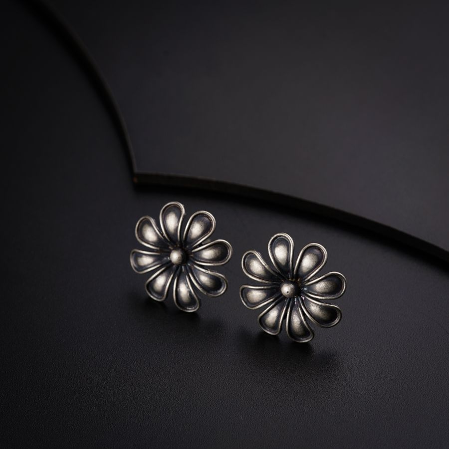 a pair of silver flower earrings on a black surface