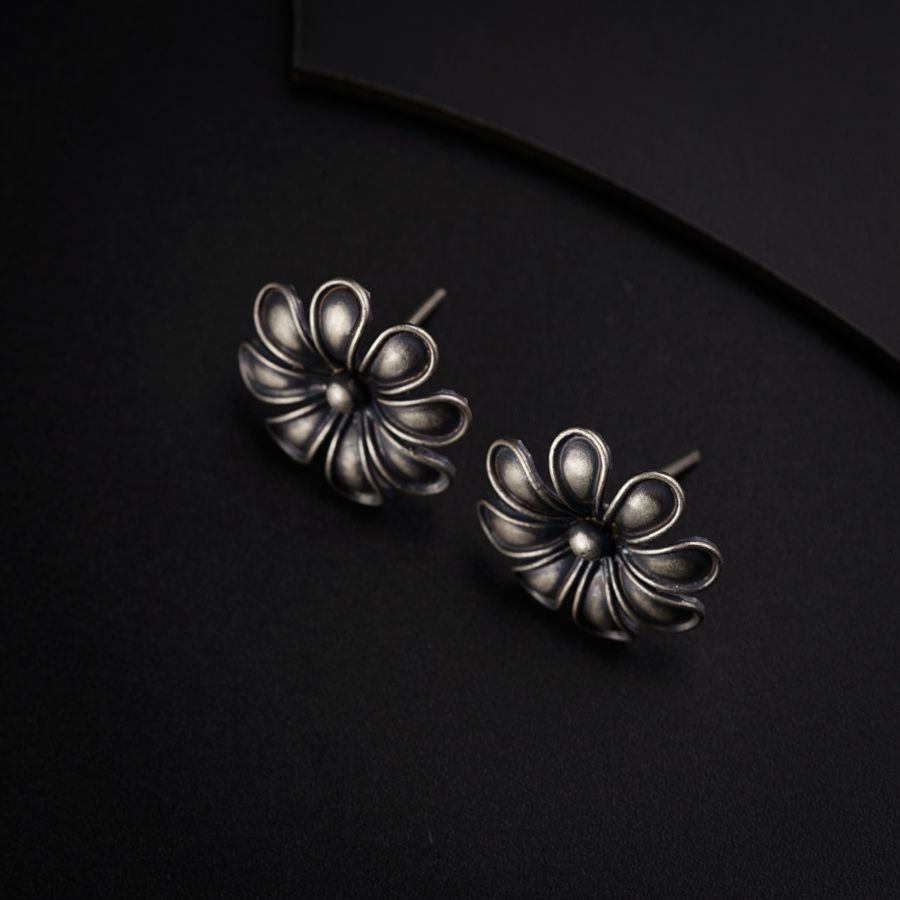 a pair of silver earrings sitting on top of a black surface