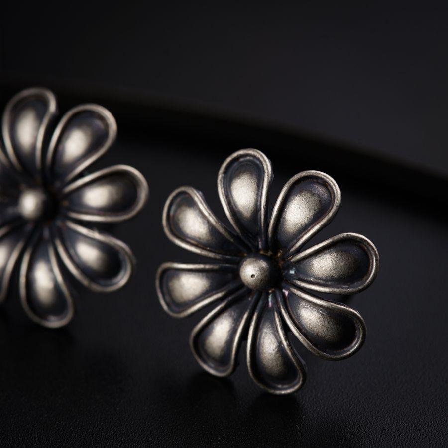 a pair of silver flower earrings on a black surface