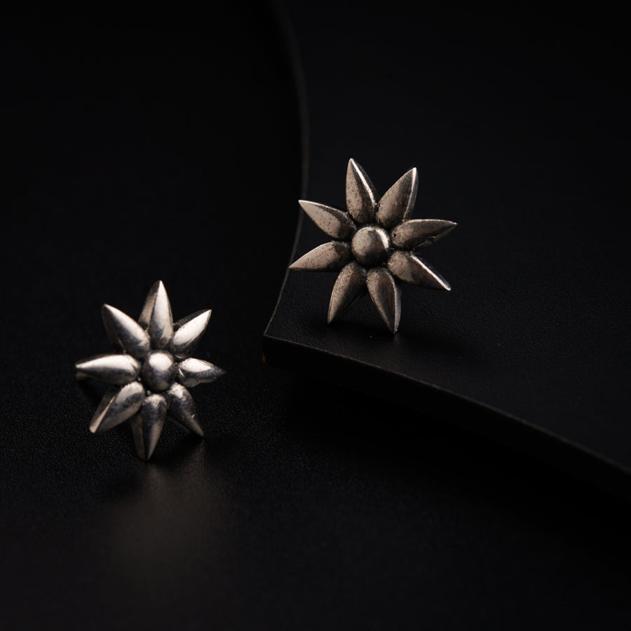 a pair of silver earrings sitting on top of a black surface