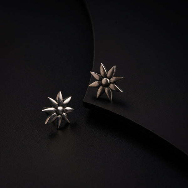 a pair of silver earrings sitting on top of a black surface
