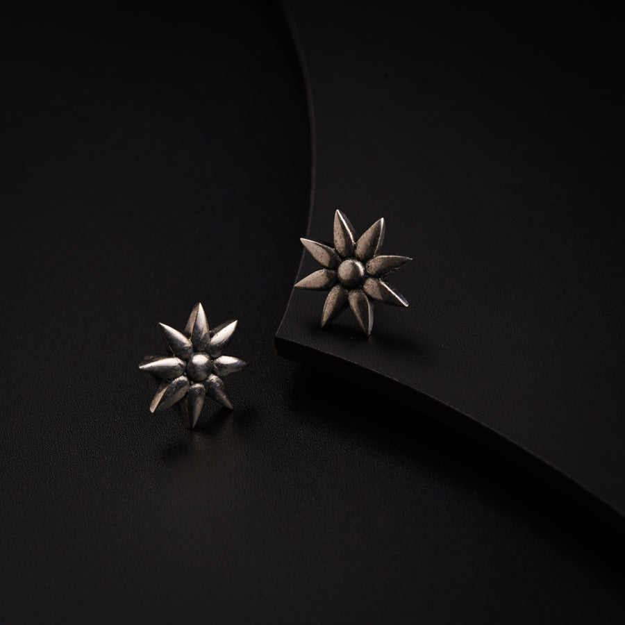 a pair of silver earrings sitting on top of a black surface
