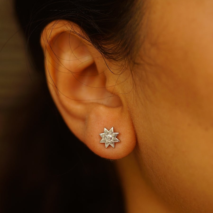 a close up of a person wearing a pair of earrings
