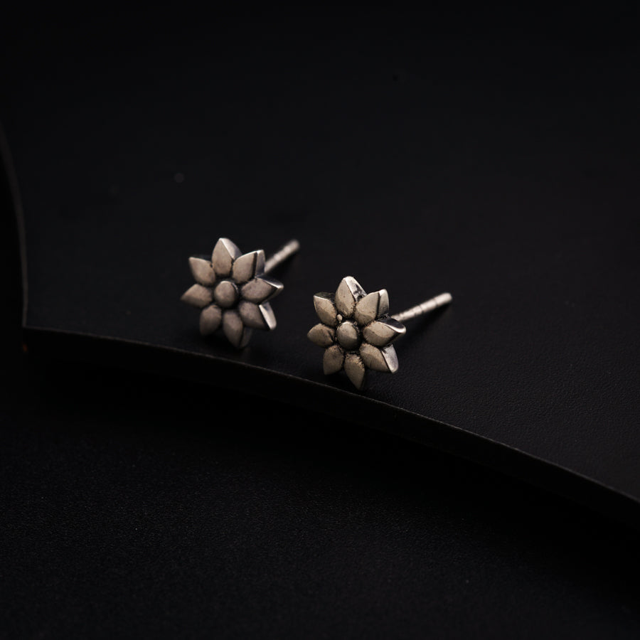 a pair of silver earrings on a black surface